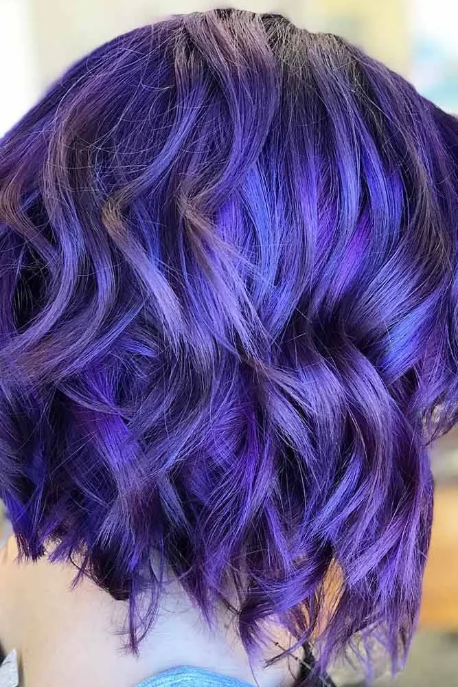 Back view of a short wavy bob colored vivid blue-violet with darker roots