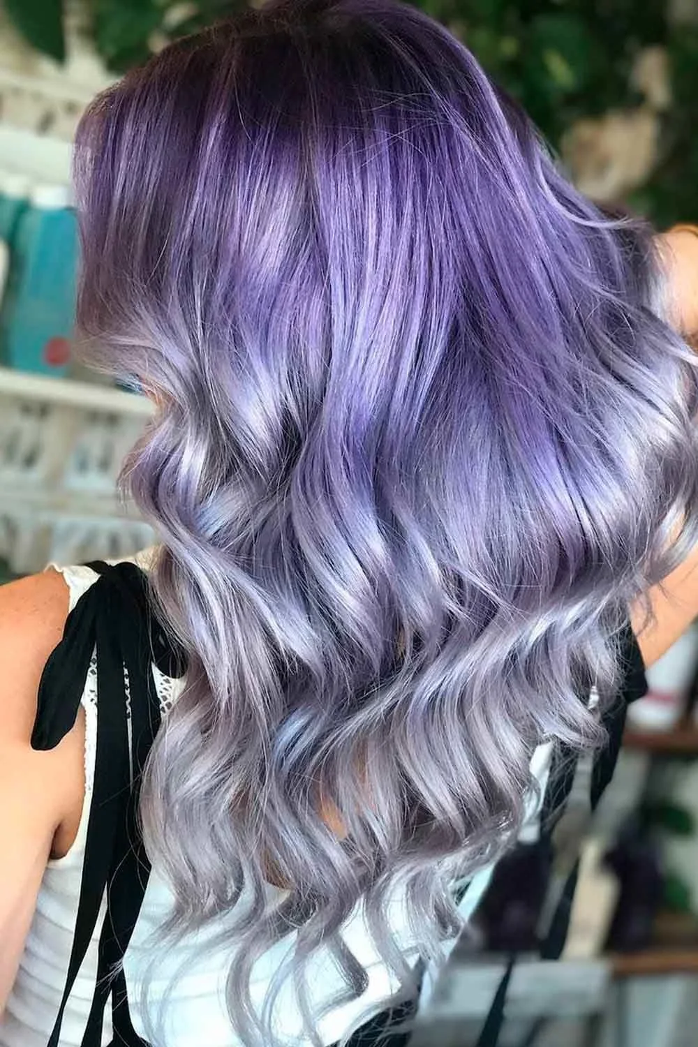 Back view of long glossy silver waves with a subtle amethyst-purple tint through the lengths