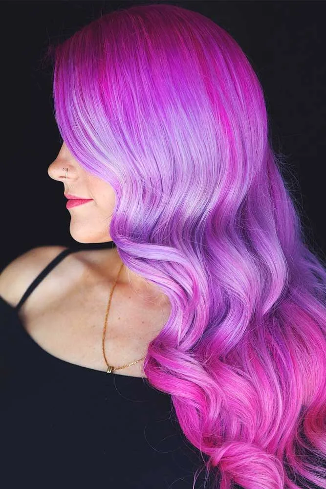 Side view of long glossy waves changing from dark magenta roots to lilac and pink-purple lengths