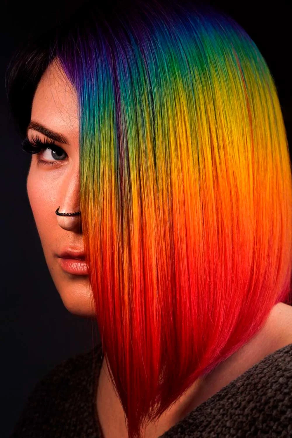 Close side view of a sleek bob with blue-green roots fading through yellow and orange into red ends