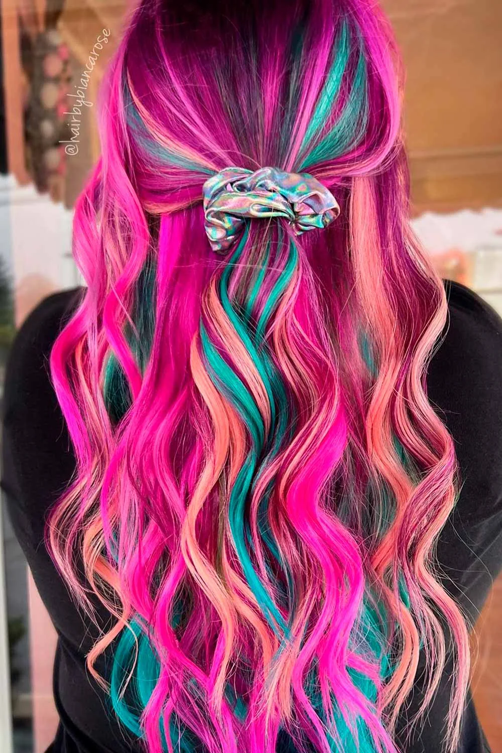 Back view of long pink waves with teal and peach ribbons gathered into a small half-up ponytail