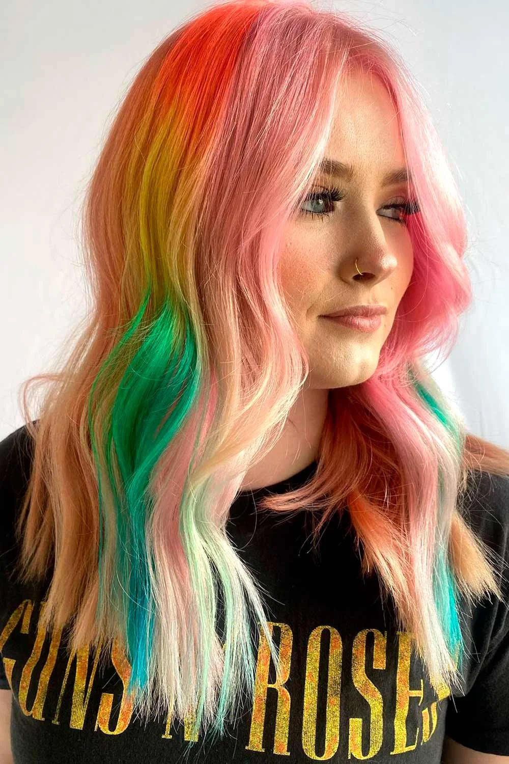 Side portrait of long pale pink hair with bright orange and green sections underneath