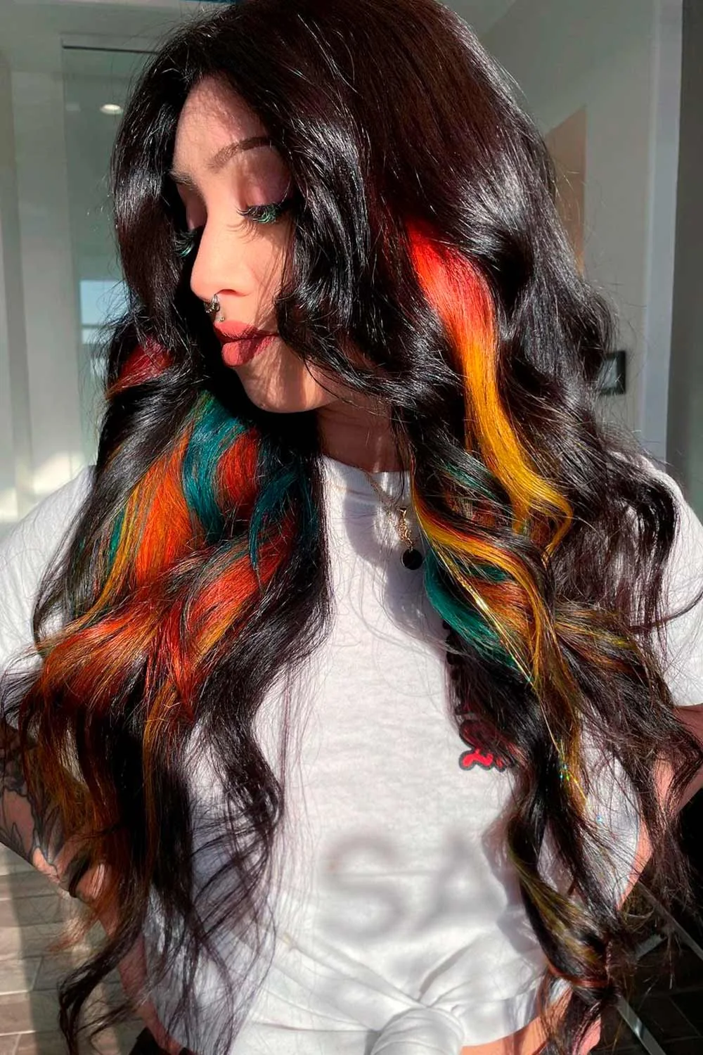 Front-side view of long dark waves with orange, yellow and turquoise ribbons underneath