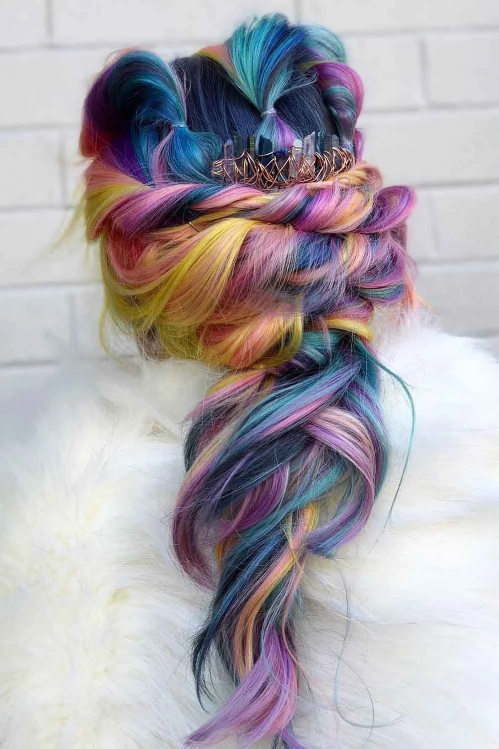 Back view of a long twisted updo with teal, violet, pink and yellow strands and decorative pins