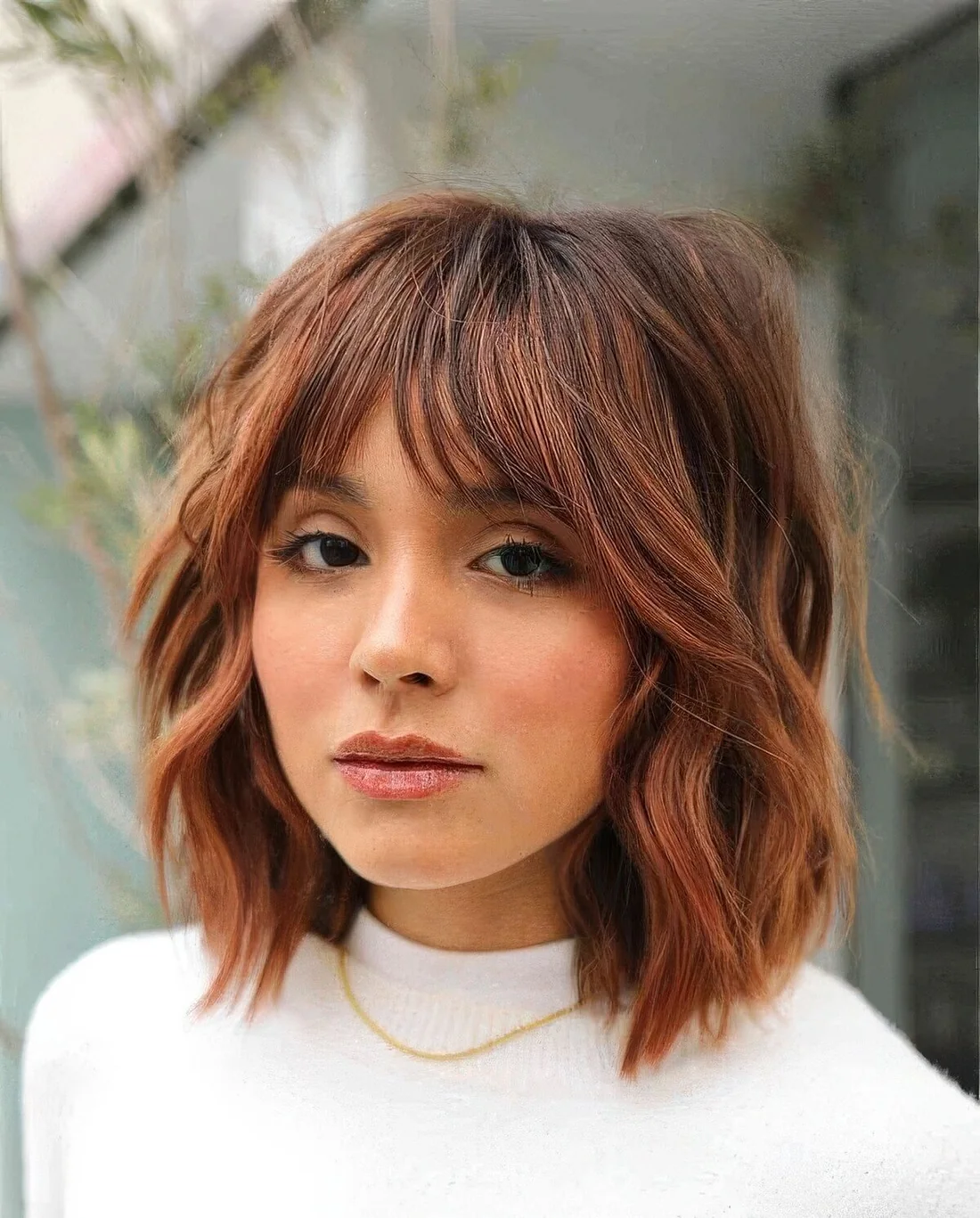 Copper shaggy long bob with a darker brown root and choppy layers.