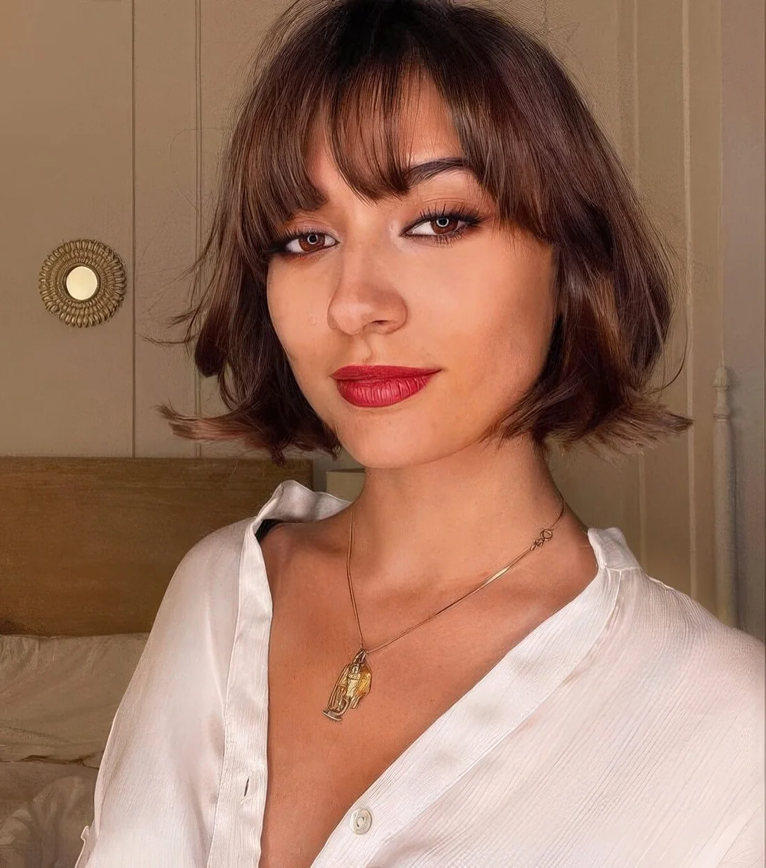 Brunette chin-length bob with wispy bangs and waves.