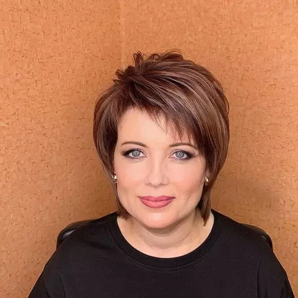 Auburn textured pixie haircut with soft volume and side movement