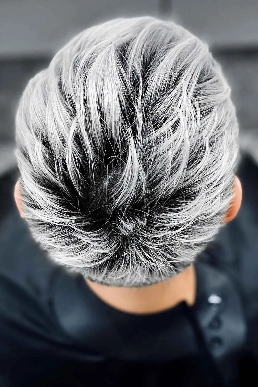 Back view of a short gray pixie with swept silver layers and a dark nape