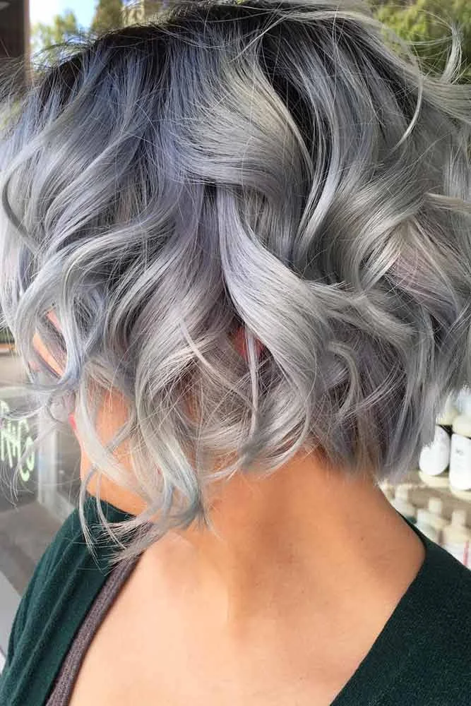 Side-back view of a short silver bob with loose curls and darker roots