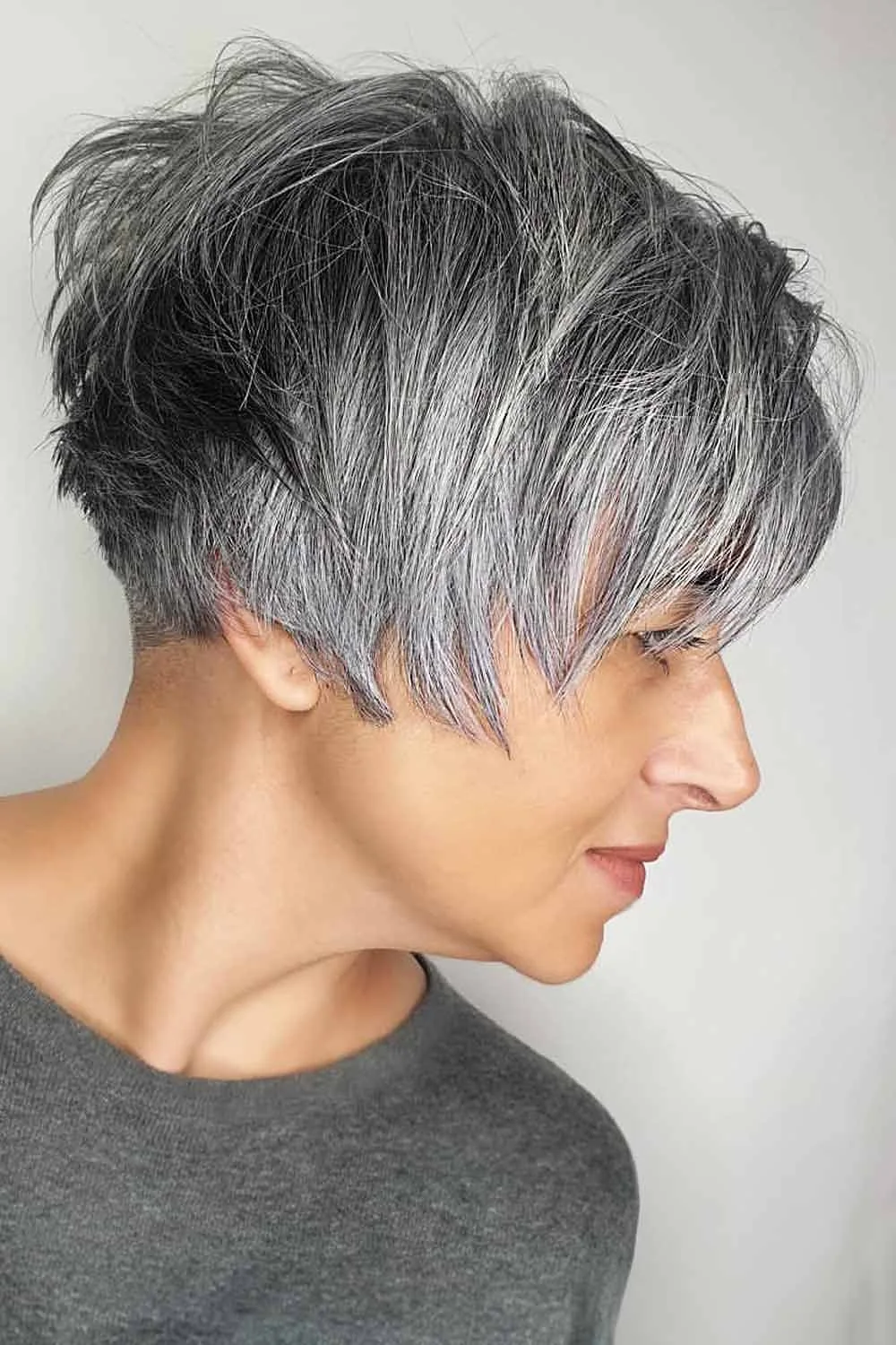 Side view of a textured salt-and-pepper pixie with a long gray fringe