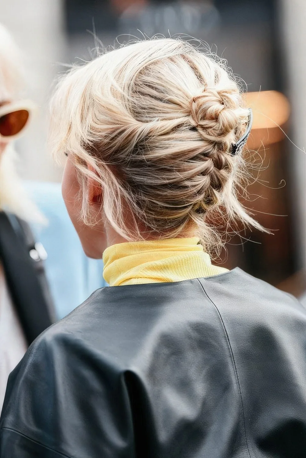 Backward braided updo with a tiny bun on top and some face-framing hair for a cool look.