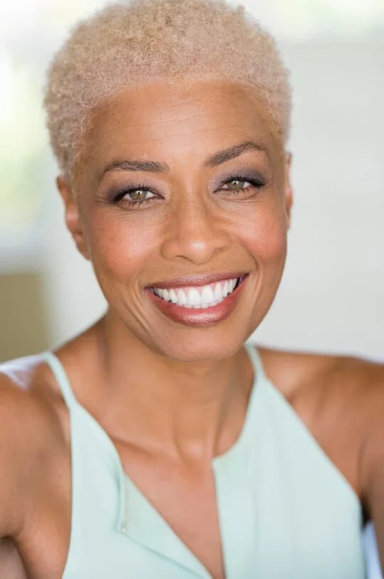 Older Black woman with a short silver coily pixie and soft curl definition
