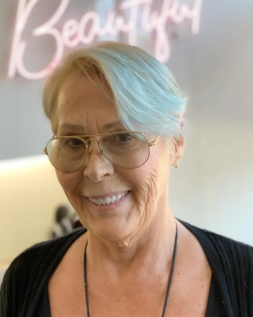 smooth silver pixie with a long diagonal top, tucked side, and softly tapered back on a round face with thin hair