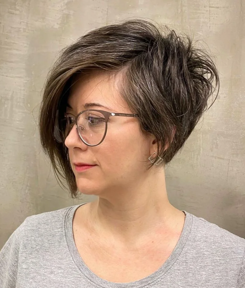 straight brunette bixie with glasses, a long side fringe, and a softly tapered nape on a round face with thin hair