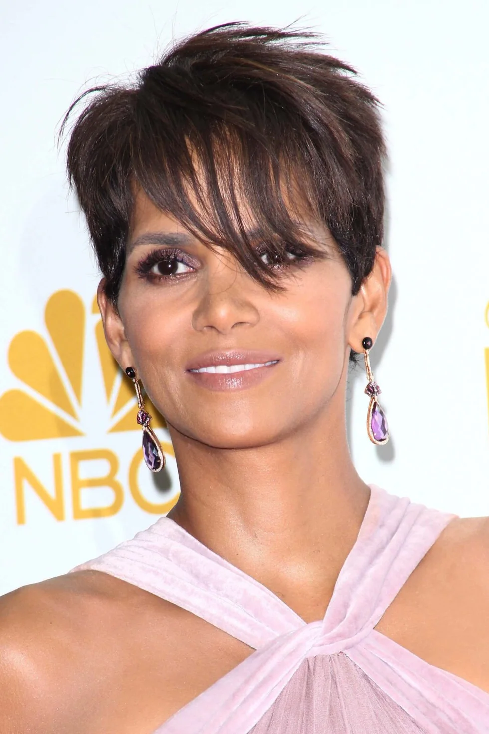 dark brunette pixie with a long sweeping fringe and closely cropped sides on a round face with thin hair