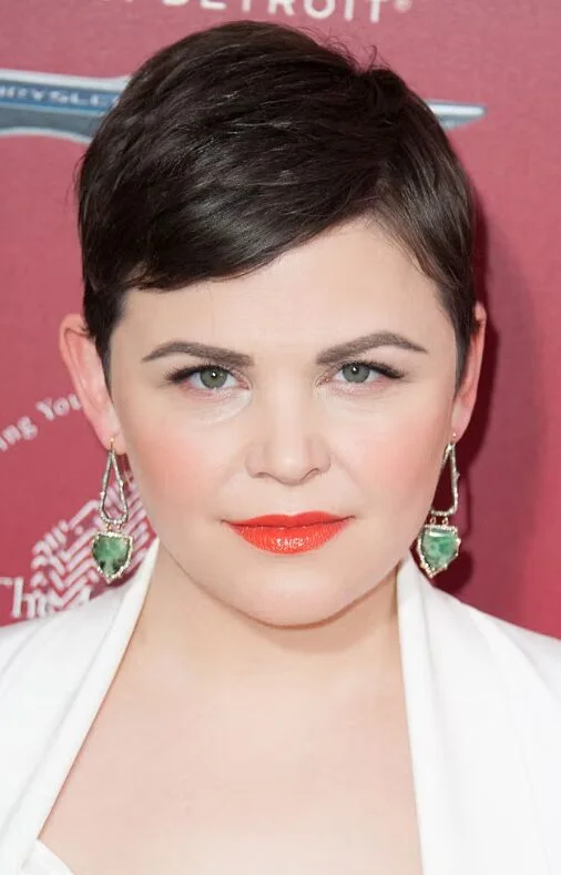 sleek black pixie with a precise side part, short fringe, and tapered sides on a round face with thin hair