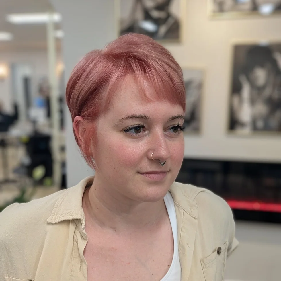 pastel pink crop with short straight bangs, neat sides, and a softly rounded crown on a round face with thin hair