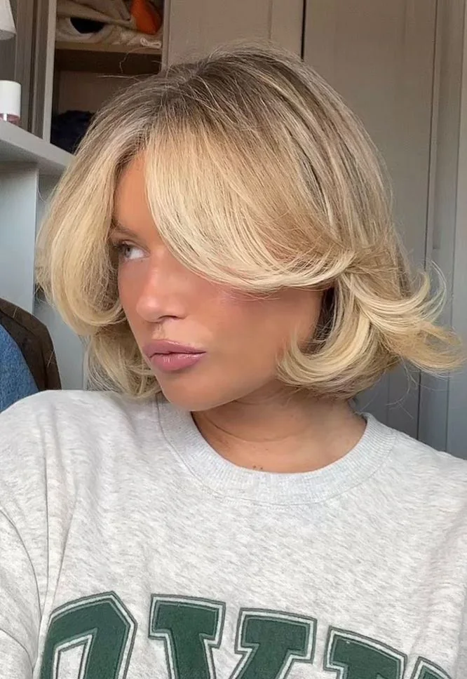 A creamy blonde butterfly bob uses broad face framing wings, a high crown, and curled under ends