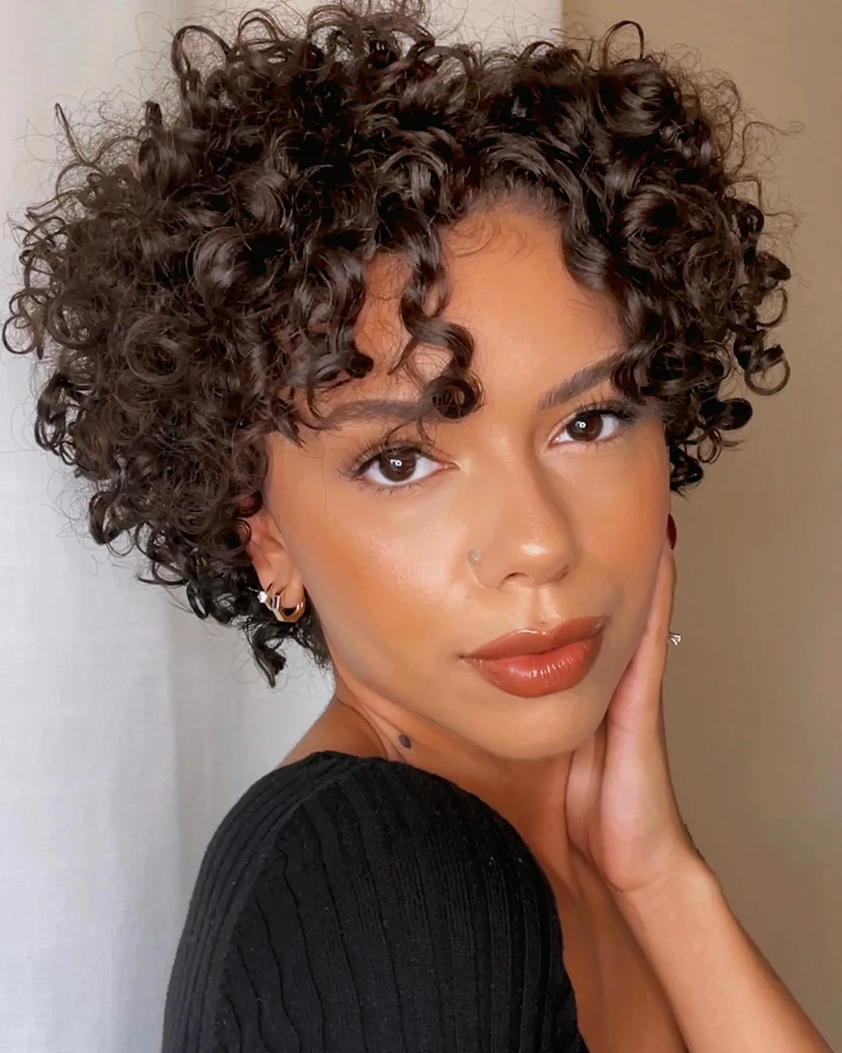 ear coily black curly style shown as a short natural hairstyles for black women over 50 idea, featuring medium layering, shown in black coily curly style with medium layering