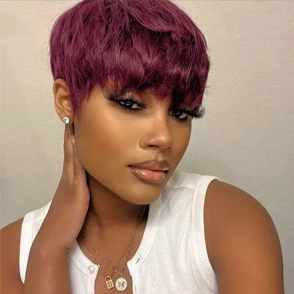 Berry colored coily pixie cut with short bangs and tapered sides