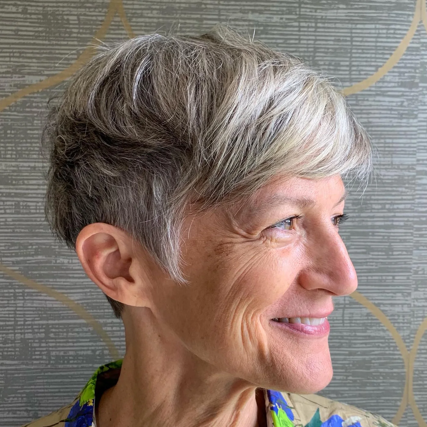Side-swept gray short pixie haircut for an older woman with soft fringe