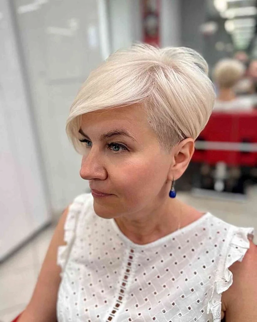 Creamy blonde side-swept short pixie haircut for an older woman