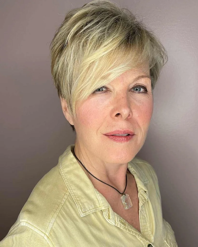 Blonde side-swept short pixie haircut for an older woman with soft fringe