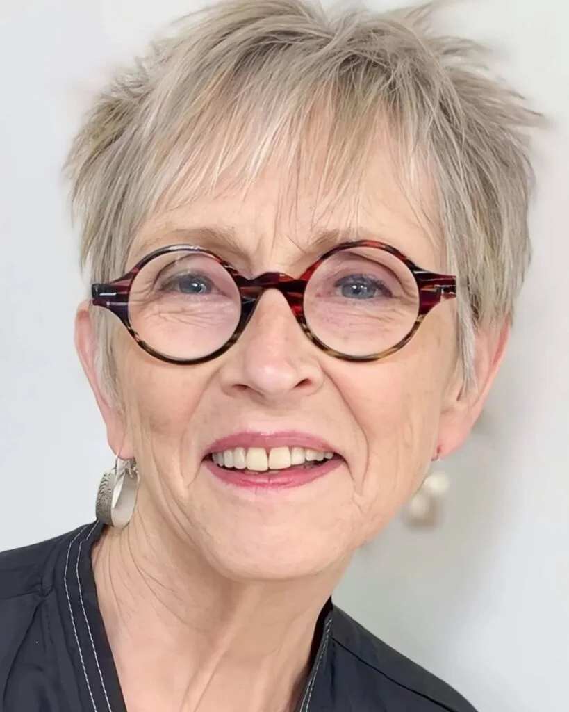 Short pixie haircut for an older woman with round glasses and soft bangs
