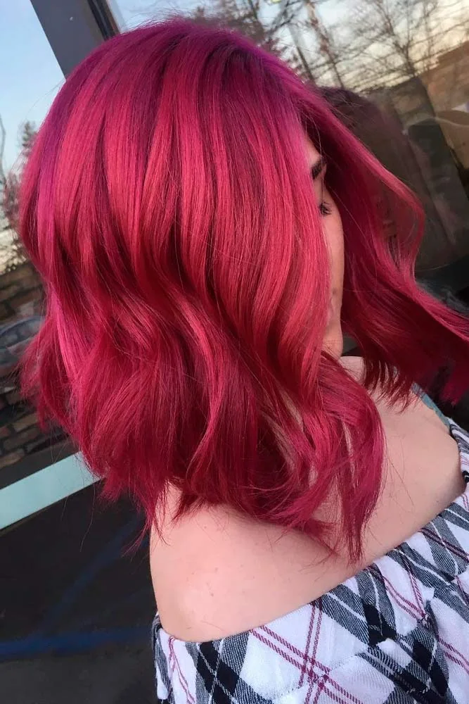 Side-back view of a short wavy bob colored bright raspberry red from crown to ends