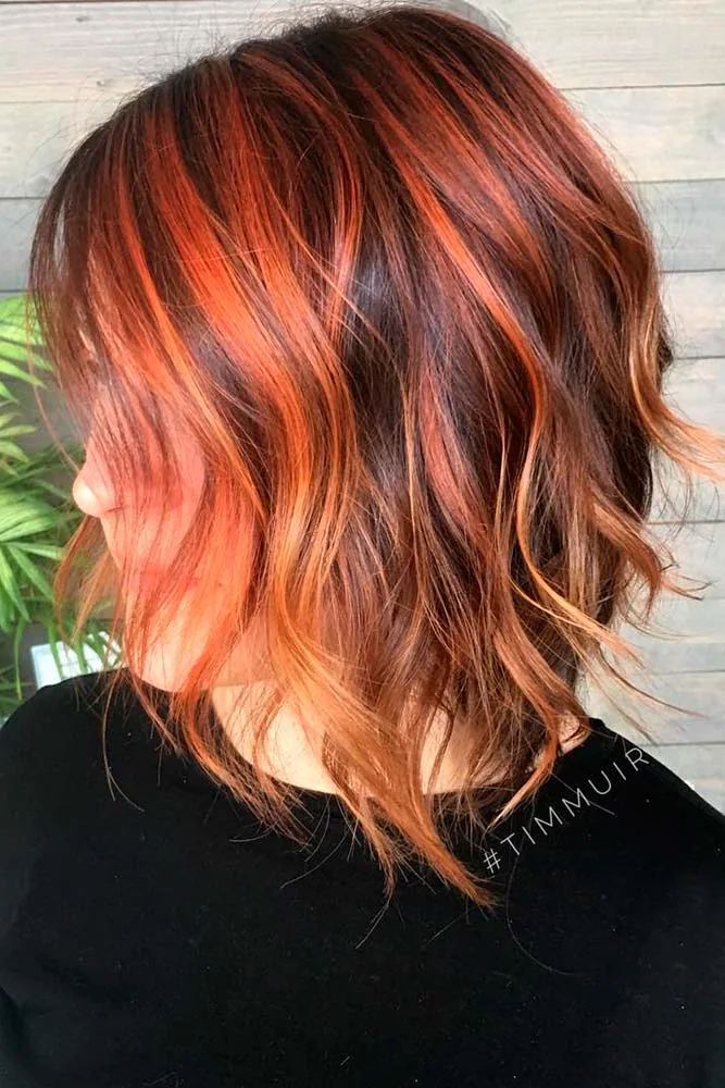 Side-back view of a short tousled lob with cinnamon-red and copper strands over a brown base