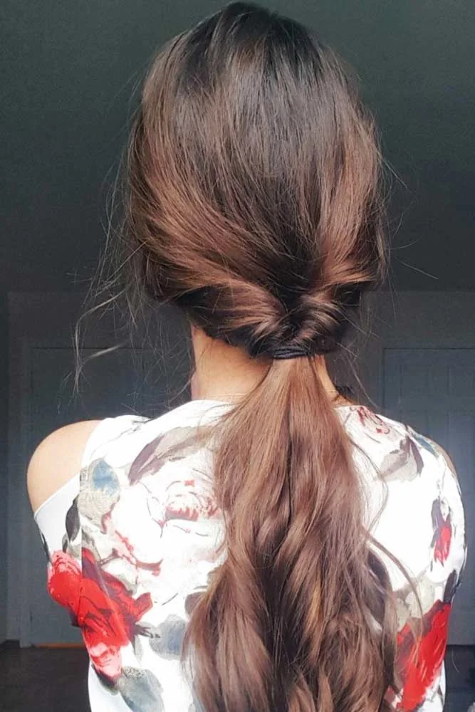 Back view of brown hair with a twisted low gathering and loose lighter ends