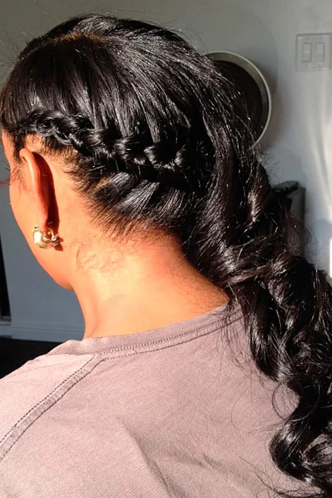 Back-side view of dark hair with a narrow side braid and a low curled ponytail