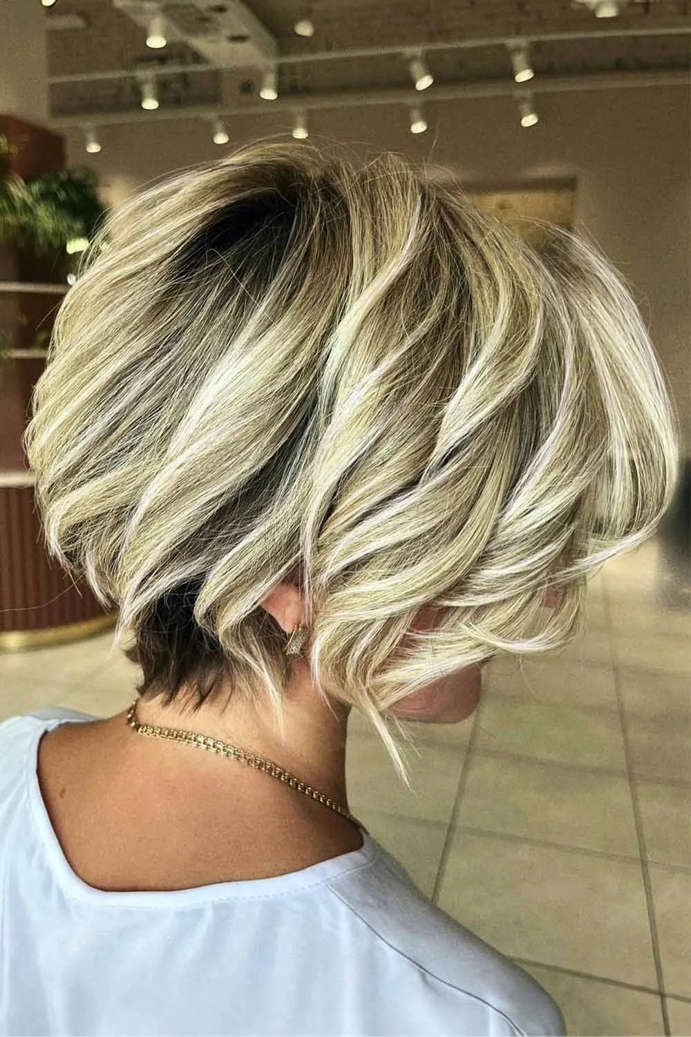 Back-side view of a blonde bob with loose waves above a short nape