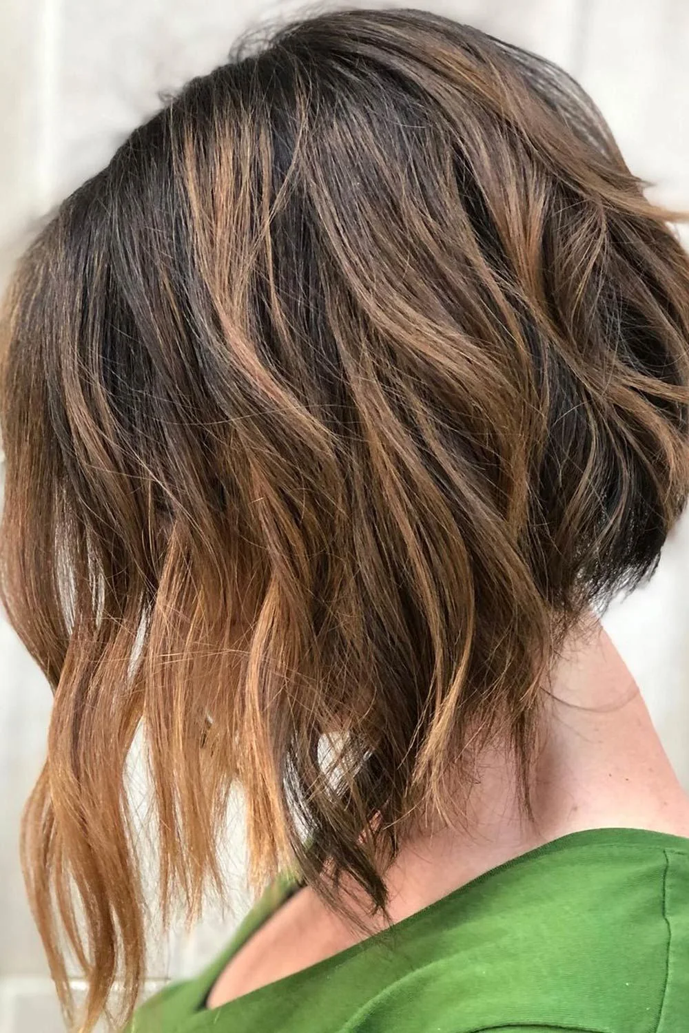 Back-side view of a brown wavy bob with a shorter back and long light front tips