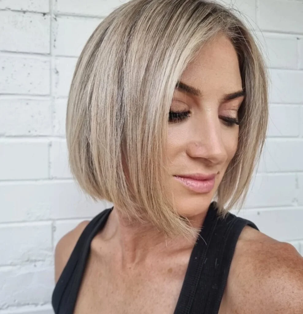 Woman with a sleek blonde angled chin-length bob and side part