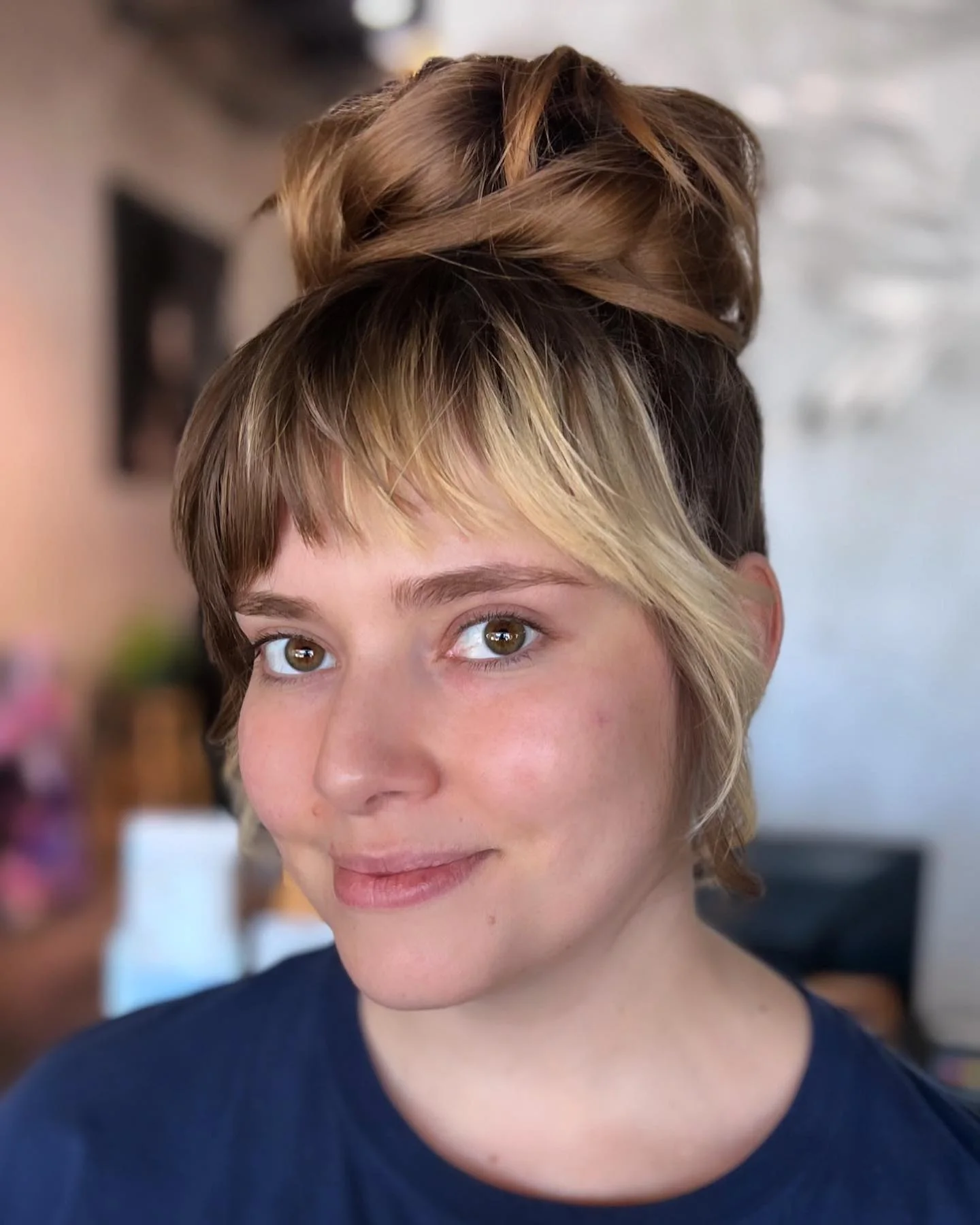 small high bun with wispy bangs with blonde straight hair styled as an updo for fine thin hair