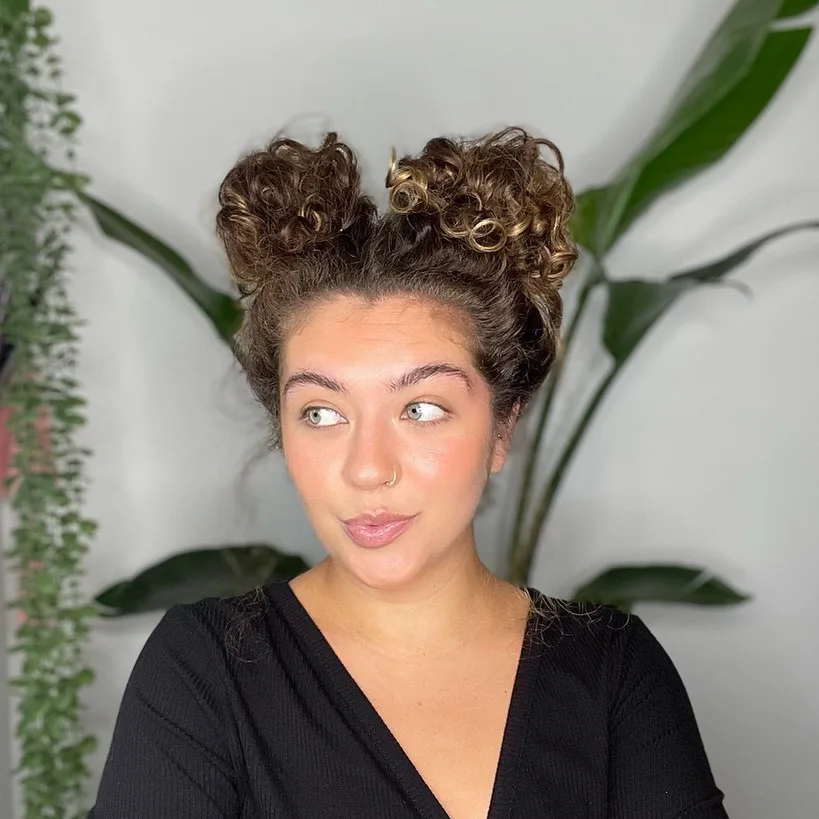 curly double bun updo with brunette curly hair styled as an updo for fine thin hair