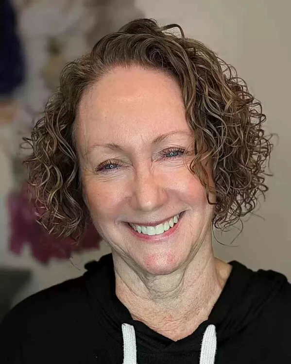 short curly gray crop on a woman over 60 with an easy wash-and-wear haircut shape