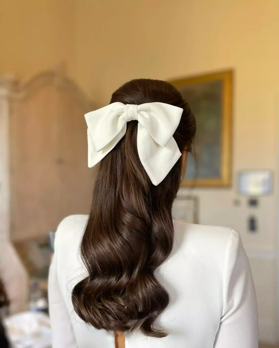 Back view of long dark wedding guest waves with a white bow