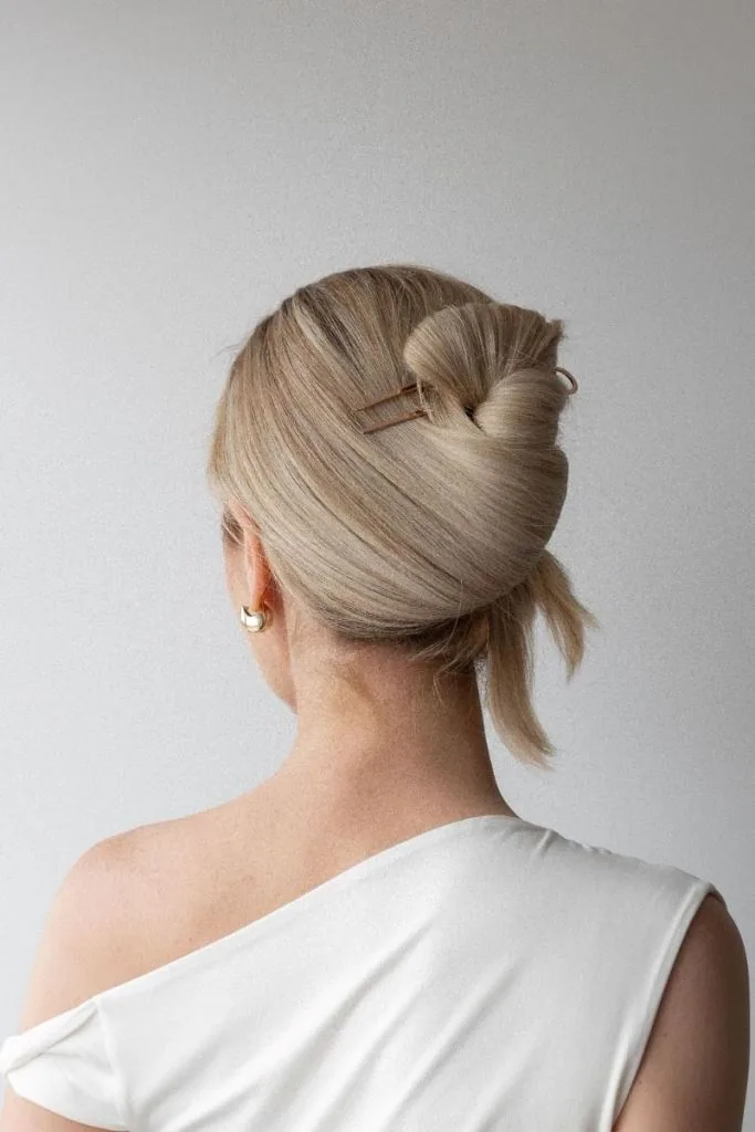 shoulder wavy blonde updo shown as a wedding guest hairstyle idea, featuring blonde color