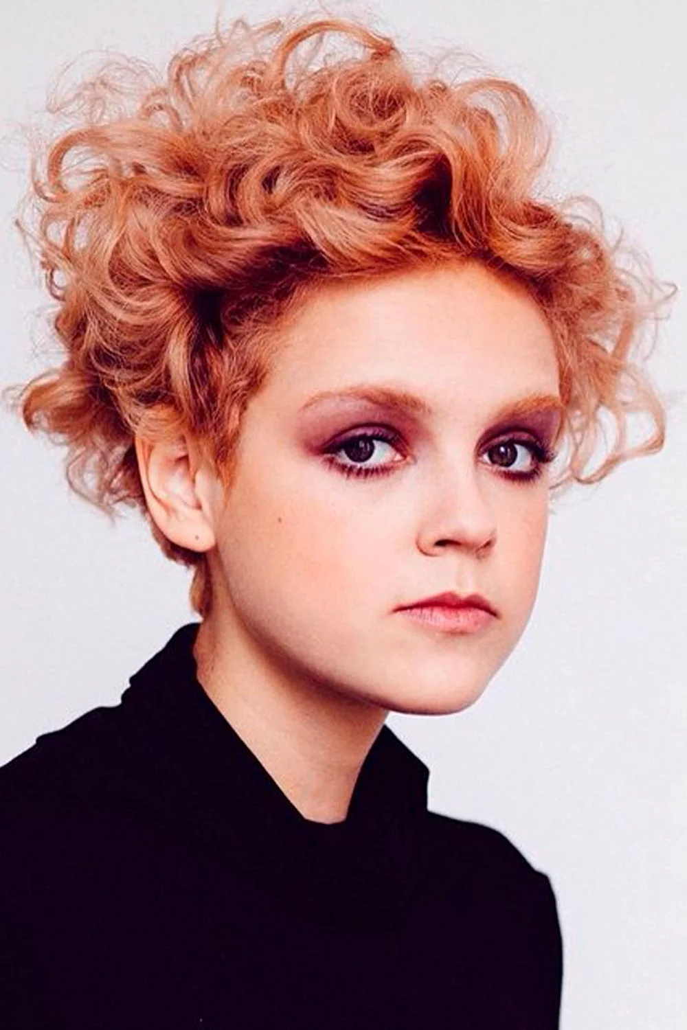 Portrait of a short curly haircut in bright copper with closely spaced curls across the crown
