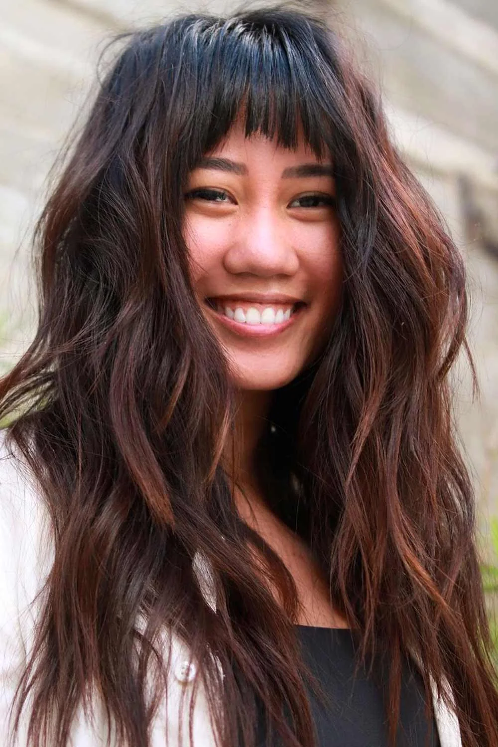 Long dark brunette waves with subtle caramel ribbons visible around the face and lower lengths