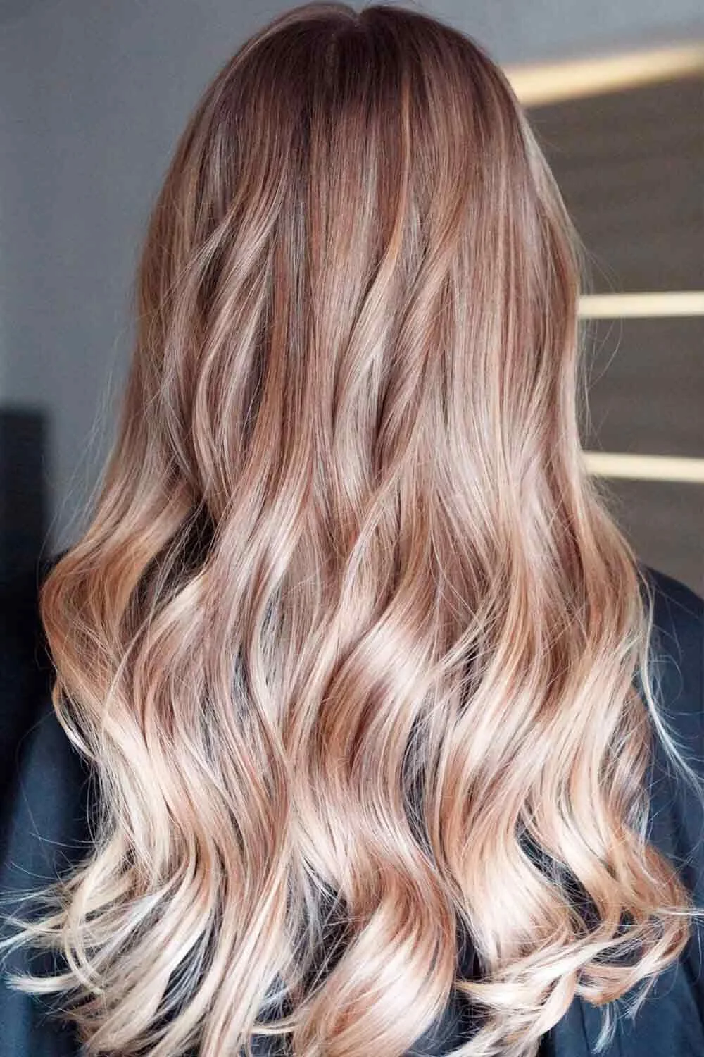 Back view of long sandy beige-blonde waves with softly blended light and darker strands