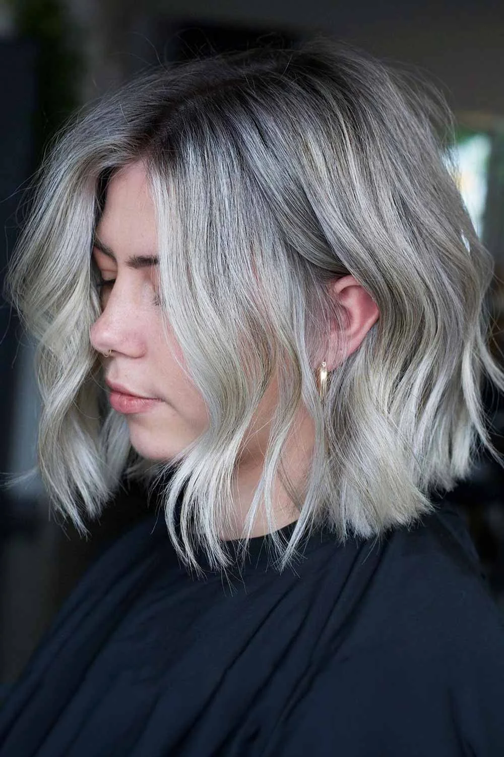 Side view of a short wavy lob in smoky silver with deeper charcoal roots