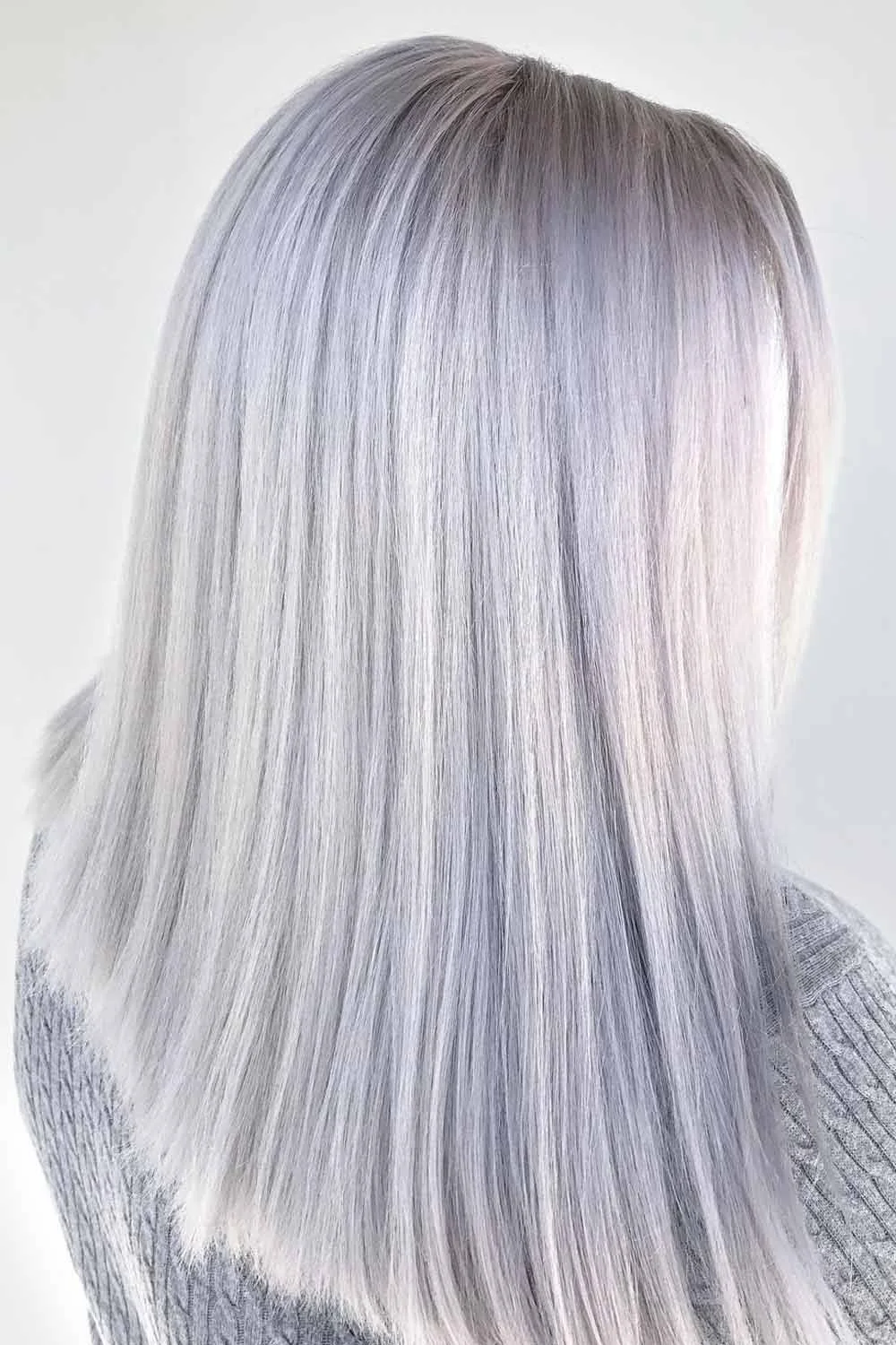 Back view of long straight platinum hair with a faint gray root shadow and blunt-looking ends