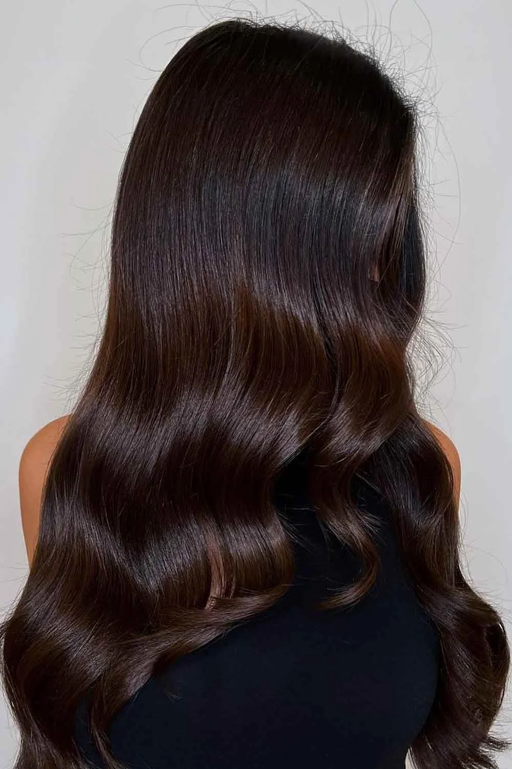 Back view of long glossy espresso-brown waves with a deep almost-black crown