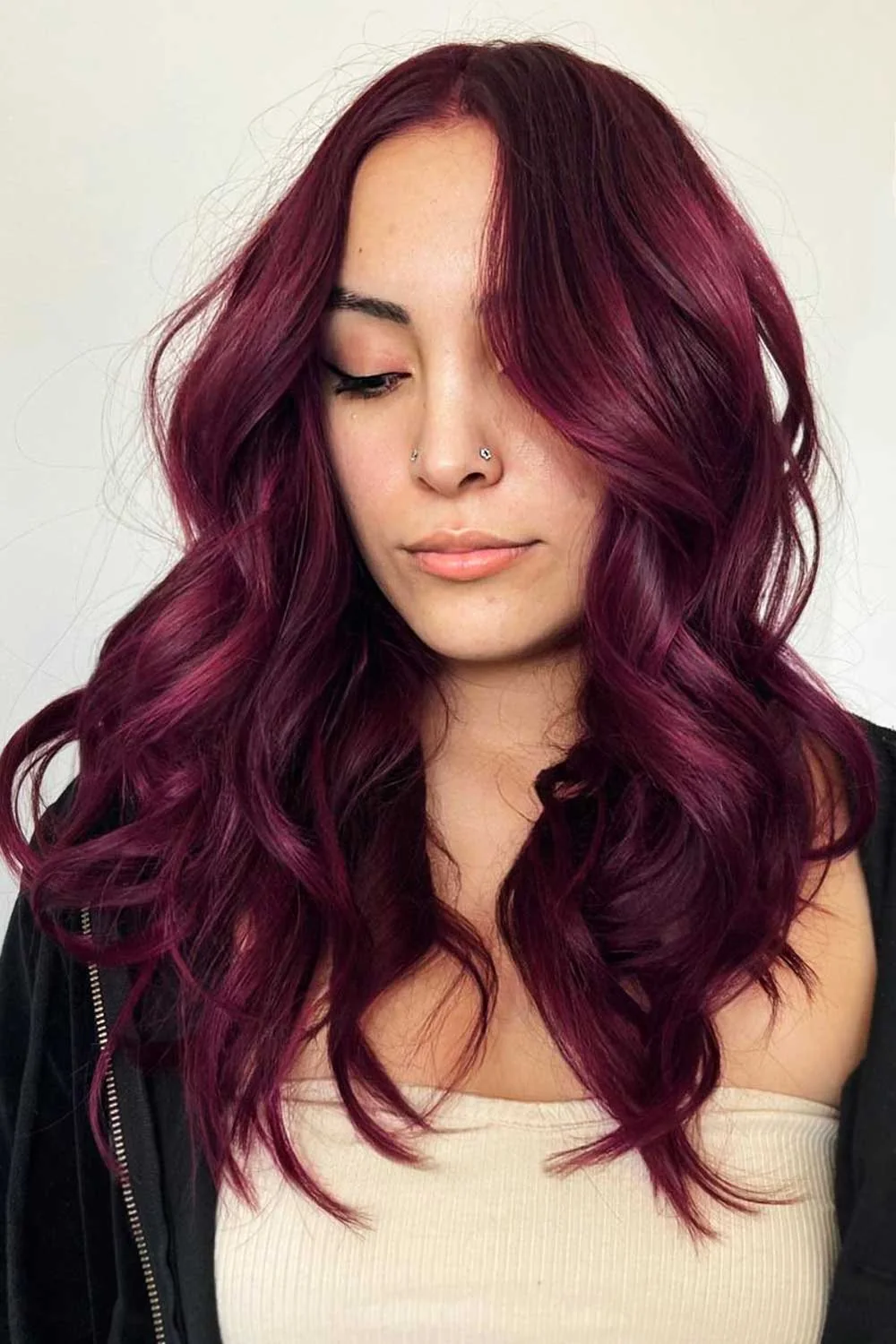 Woman with shoulder-length waves in a deep mahogany-red shade and a slightly darker crown