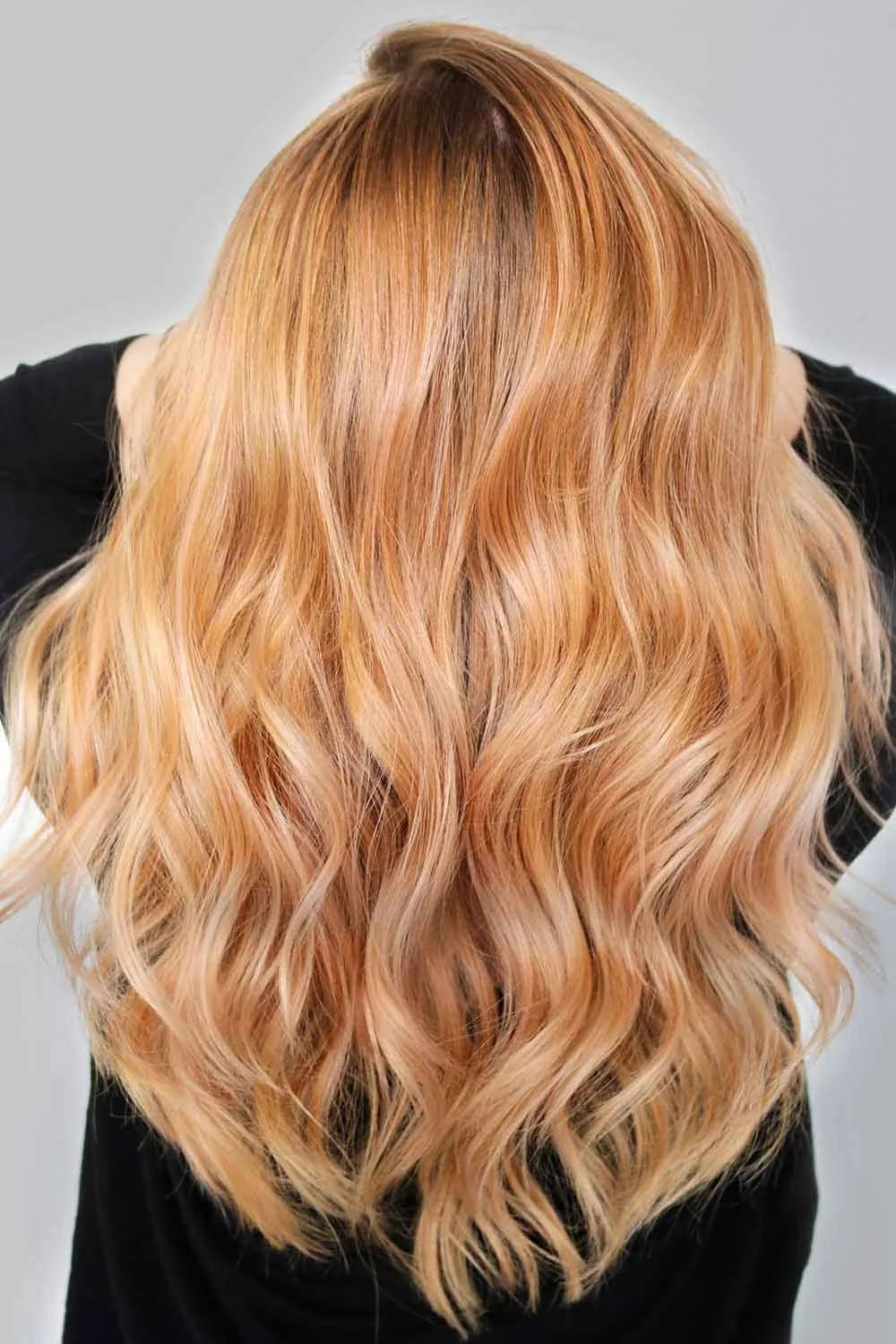 Back view of long loose waves in a soft strawberry-blonde mix of pale gold and copper