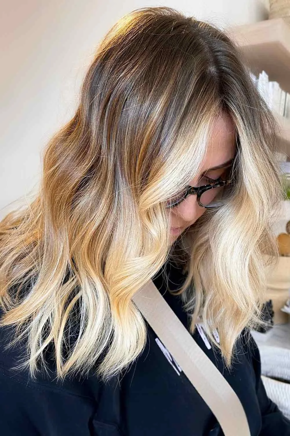 Side view of wavy shoulder-length hair with dark brown roots and wide pale blonde pieces around the face